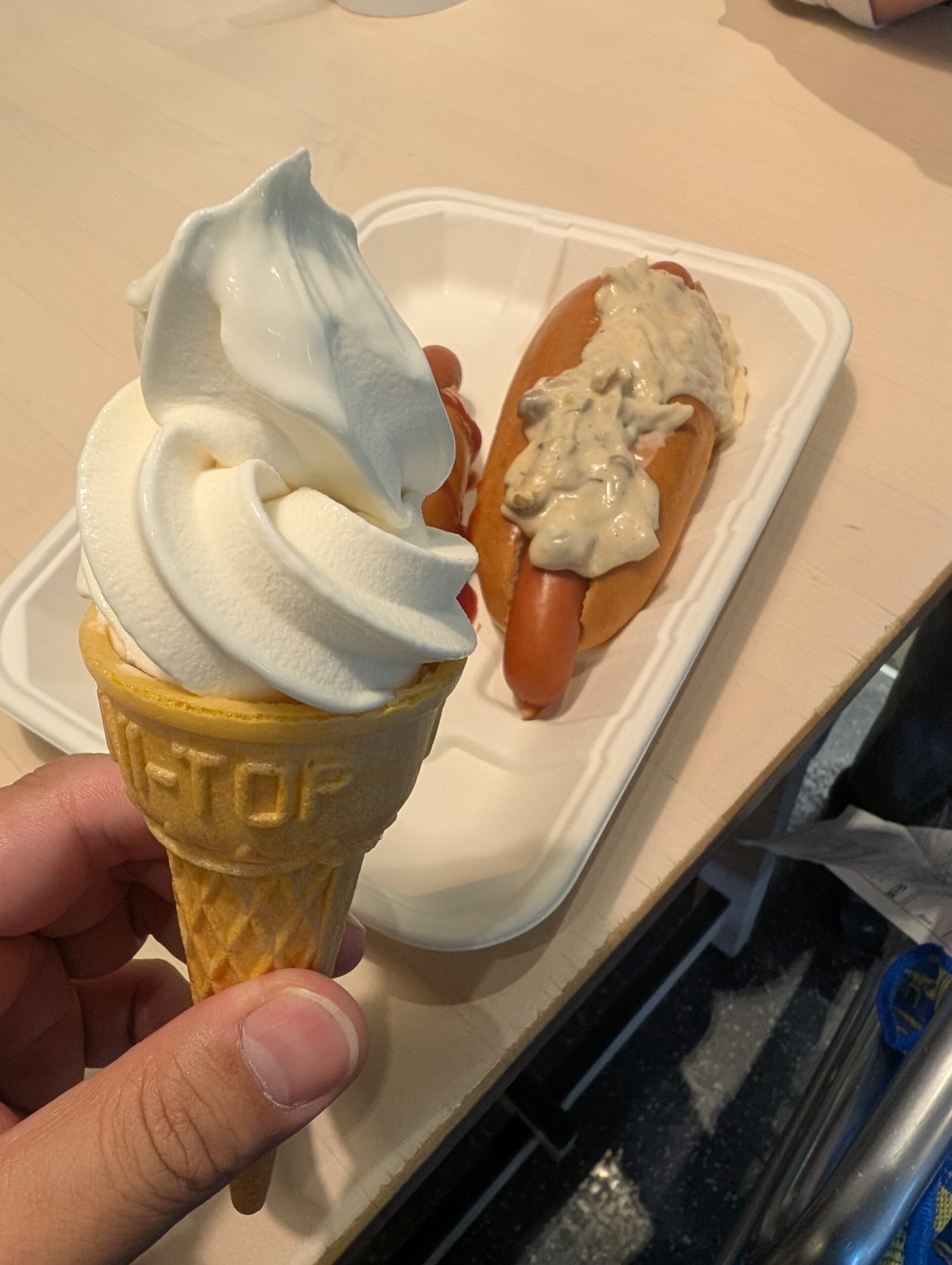 soft-serve-ice-cream-hotdog ワッフルコーンのソフトクリームを手で持っている様子と、トレイに乗せられたマッシュルームソースのかかったホットドッグが写っている写真。